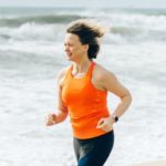 Woman in orange runs on beach