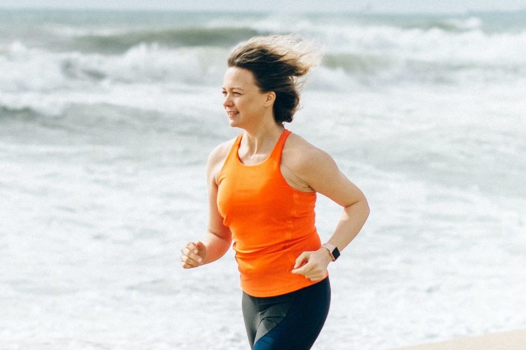 Woman in orange runs on beach