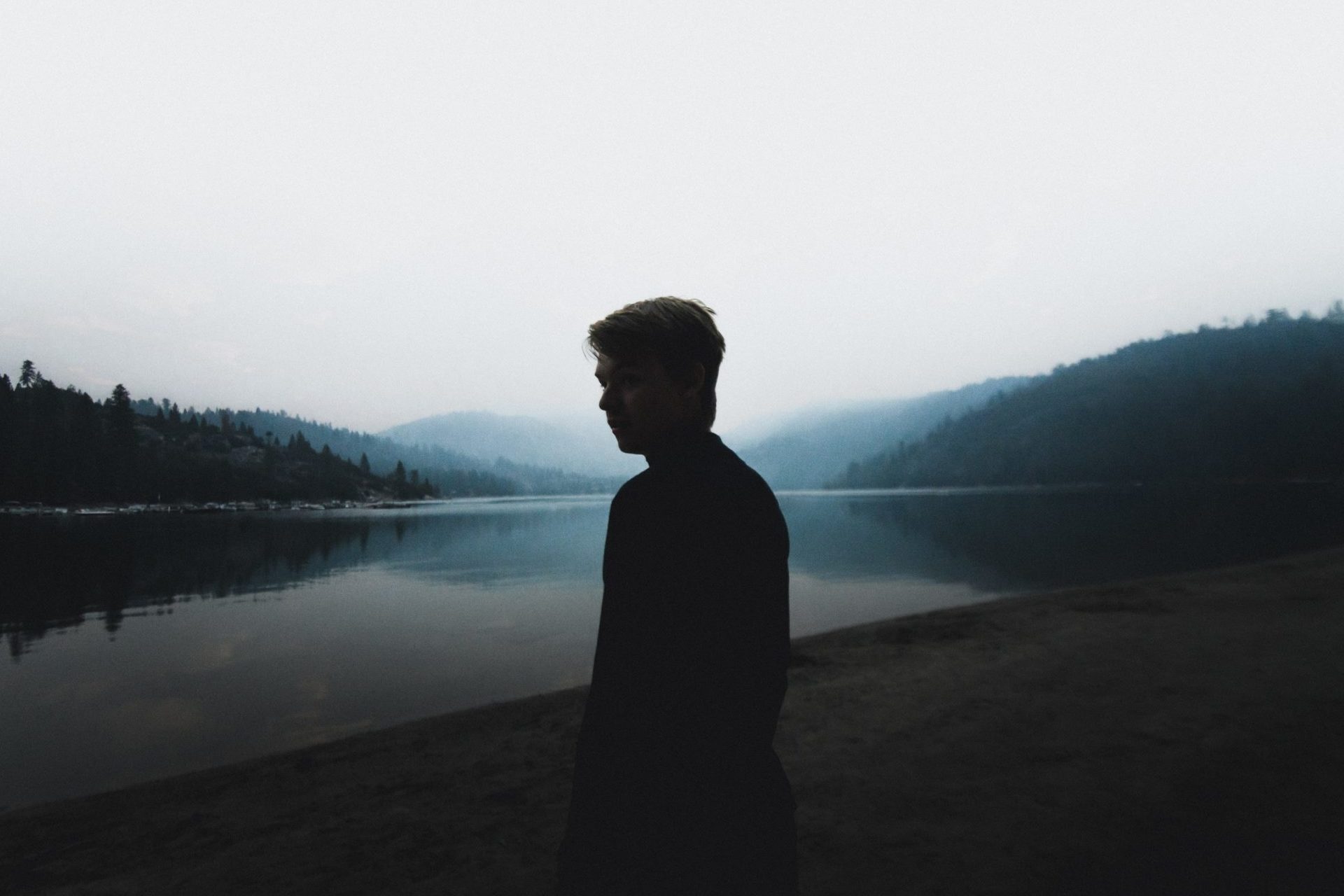 Silhouette of a man standing by a lake