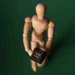 wooden figurine holds a pause button