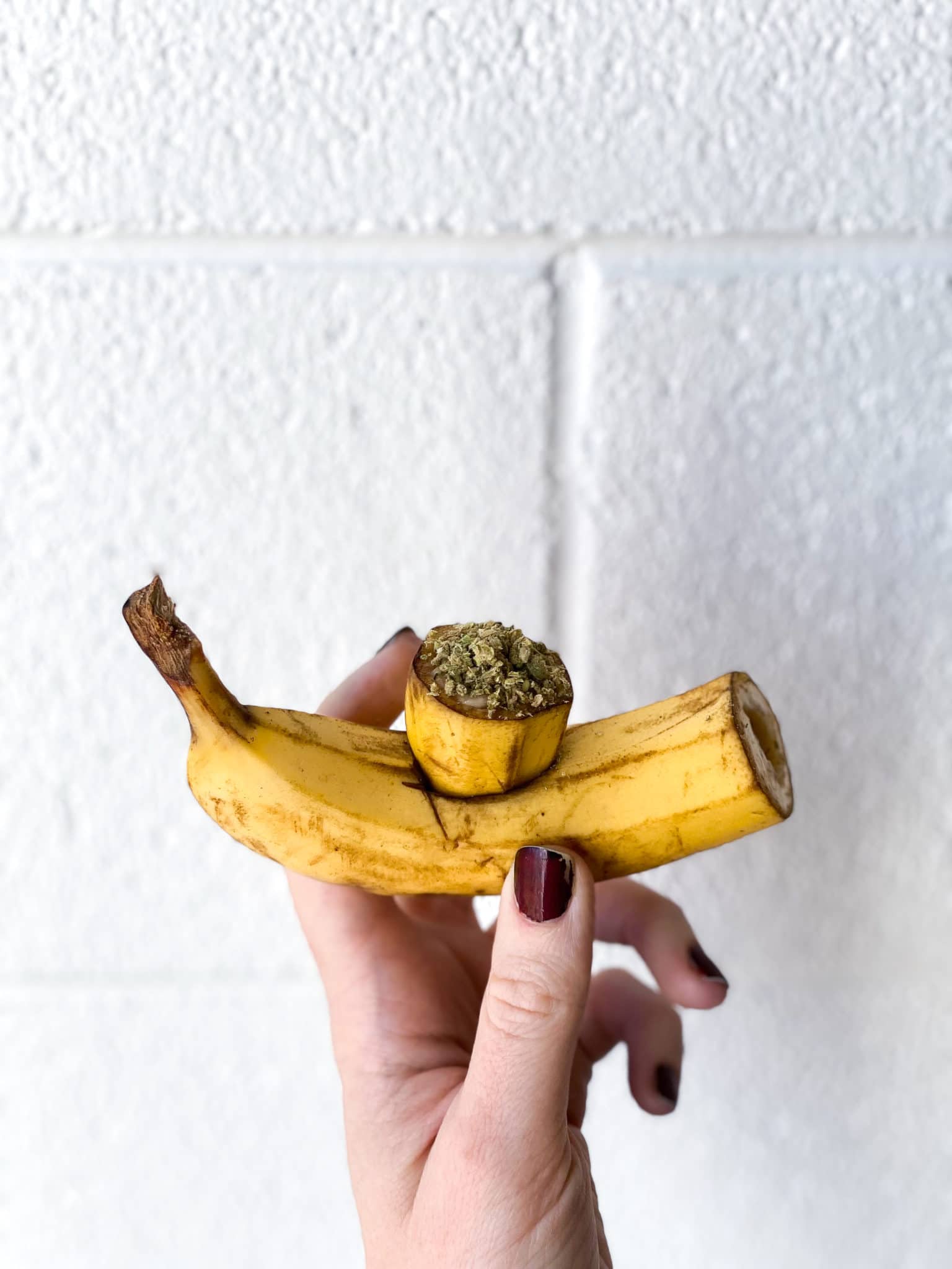 hand holding a DIY banana pipe with cannabis flower