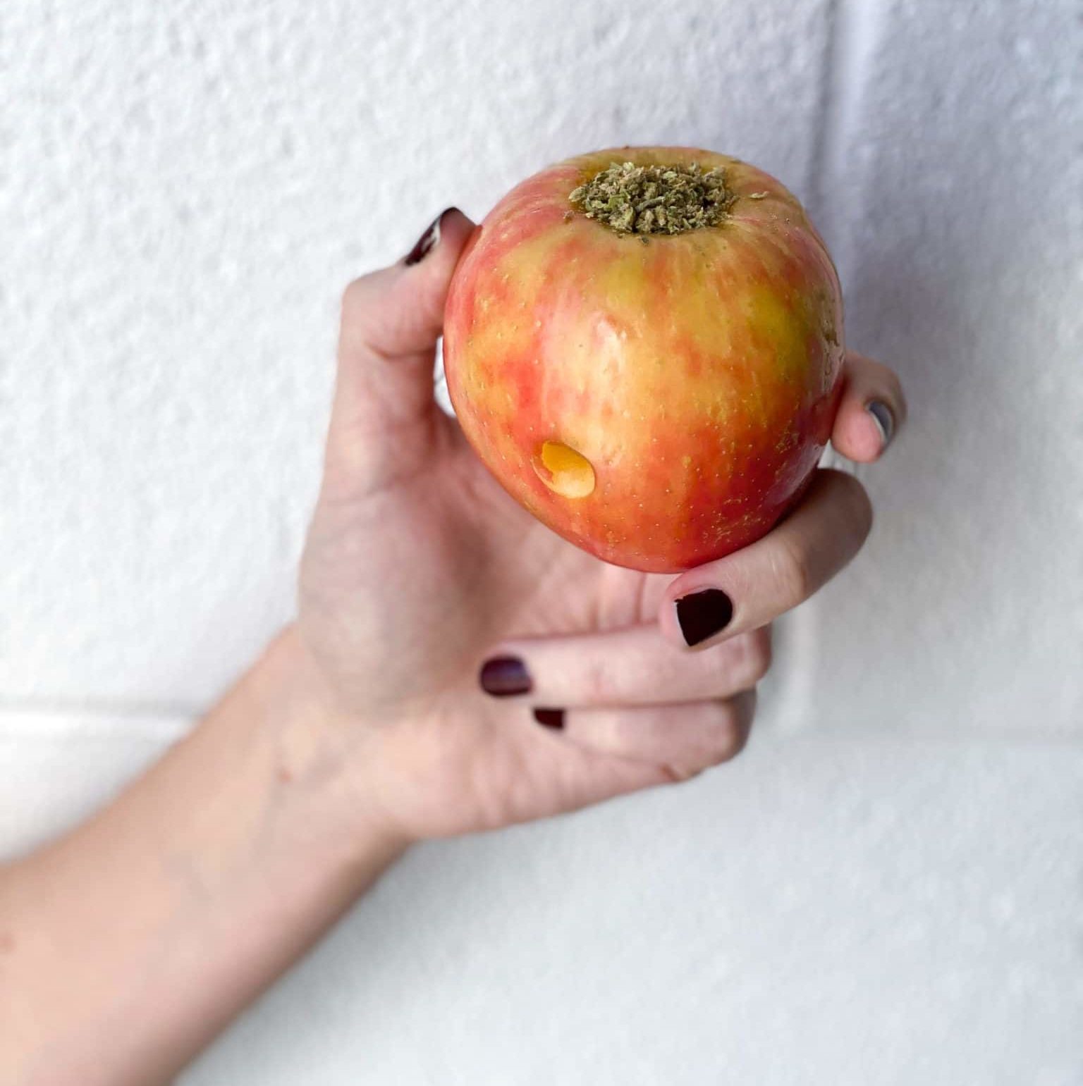 hand holding a DIY apple pipe with cannabis flower