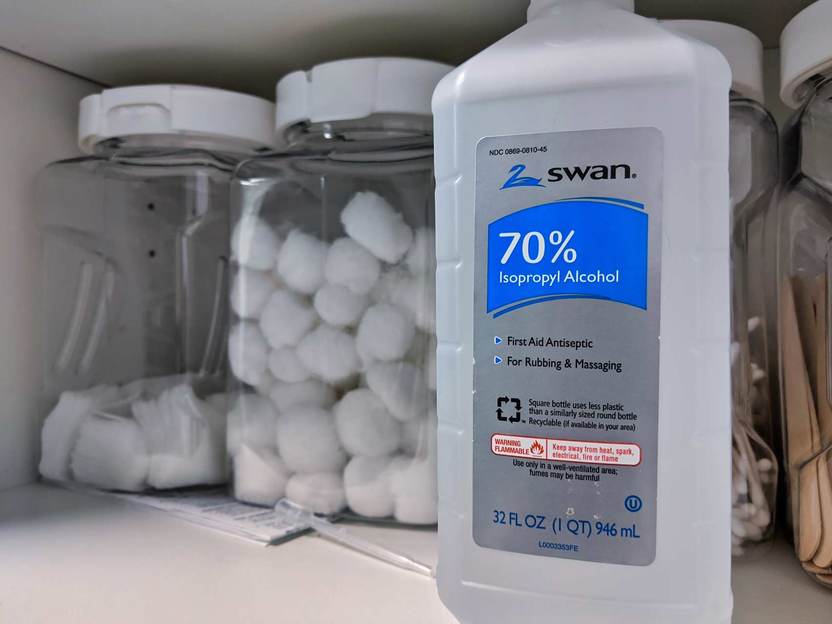 isopropyl alcohol on shelf next to jars of cotton balls and q-tips
