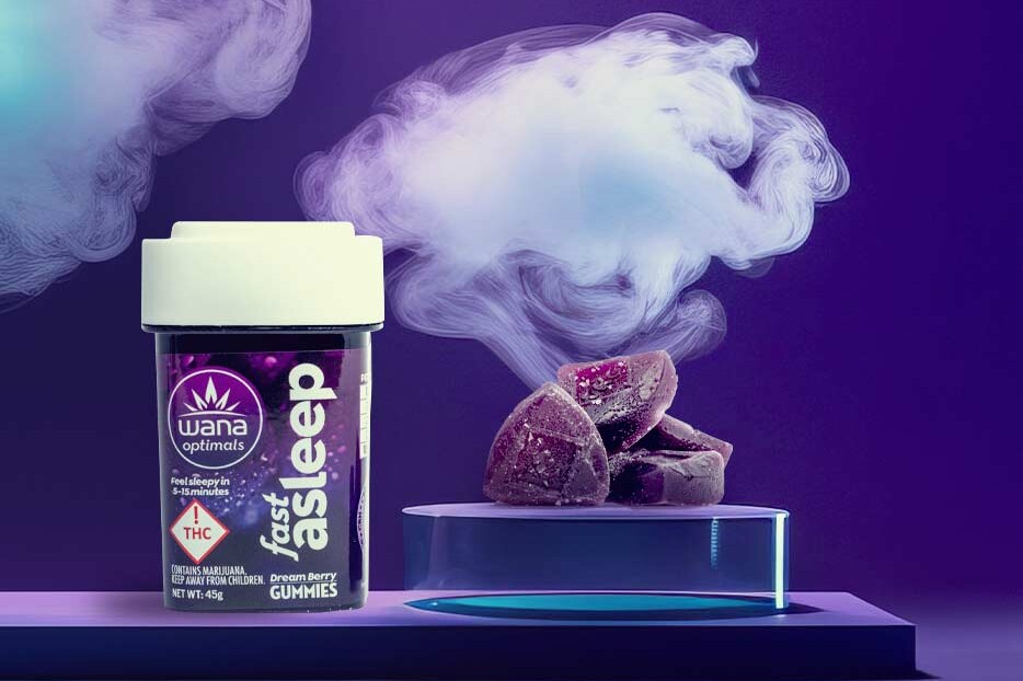 Container of Wana Optimals Fast Asleep Dream Berry THC sleep gummies next to a stack of purple gummies on a glowing pedestal, with swirling vapor in the background.